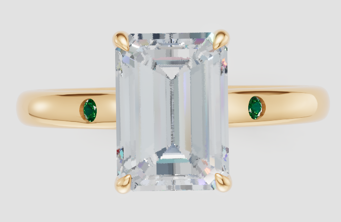 Emerald cut lab-grown diamond ring with yellow gold band and green side stones, ethical engagement ring
