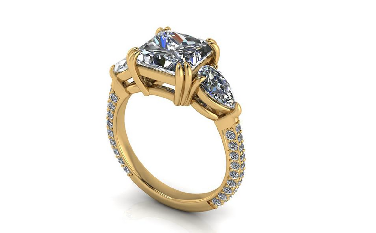 A yellow gold three-stone ring featuring a square princess-cut center stone and two marquise-cut side stones, accented with small pavé diamonds on the band, shown on a white background.